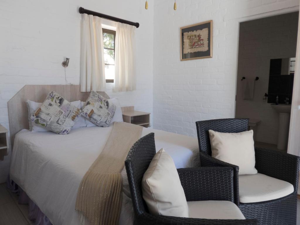 a bedroom with a bed and two chairs at Myrtles Retreat in Stilbaai