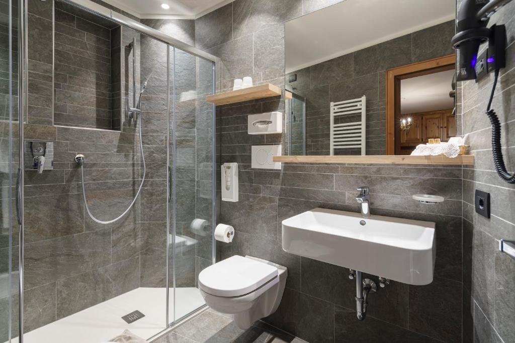 łazienka z toaletą, umywalką i prysznicem w obiekcie Hotel Columbia & Spa w mieście Cortina dʼAmpezzo