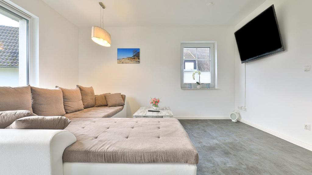 ein Wohnzimmer mit einem Sofa und einem Flachbild-TV in der Unterkunft Fischerjung in Born
