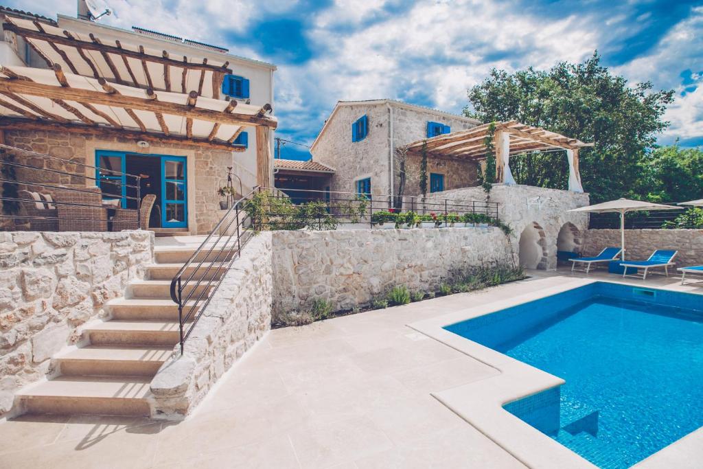 a house with a swimming pool next to a stone wall at Villa DELUXE in Gabonjin