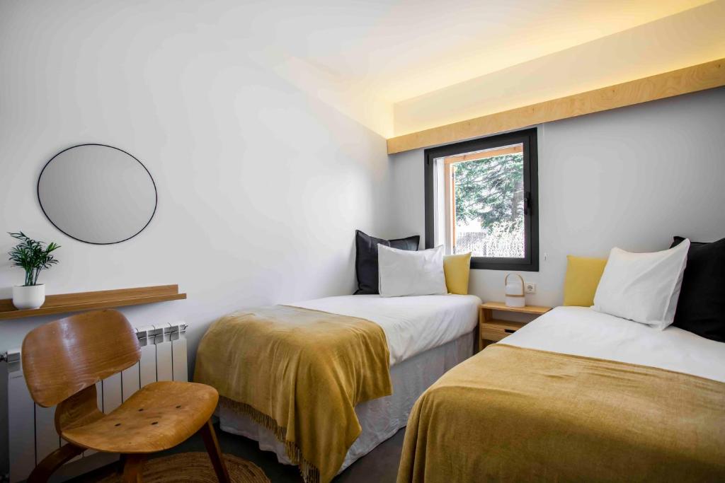 Habitación con 2 camas, silla y espejo. en Finca el Veinti9, en Navacerrada
