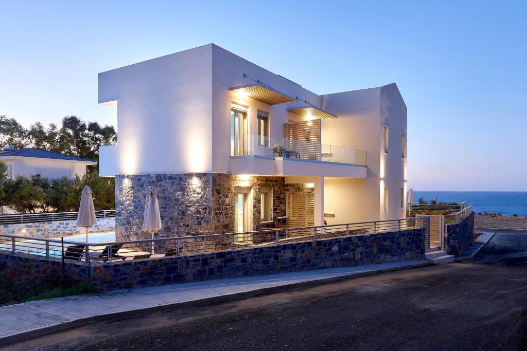 uma grande casa branca com o oceano ao fundo em Theasea Stylish Residences em Panormos - Rethymno