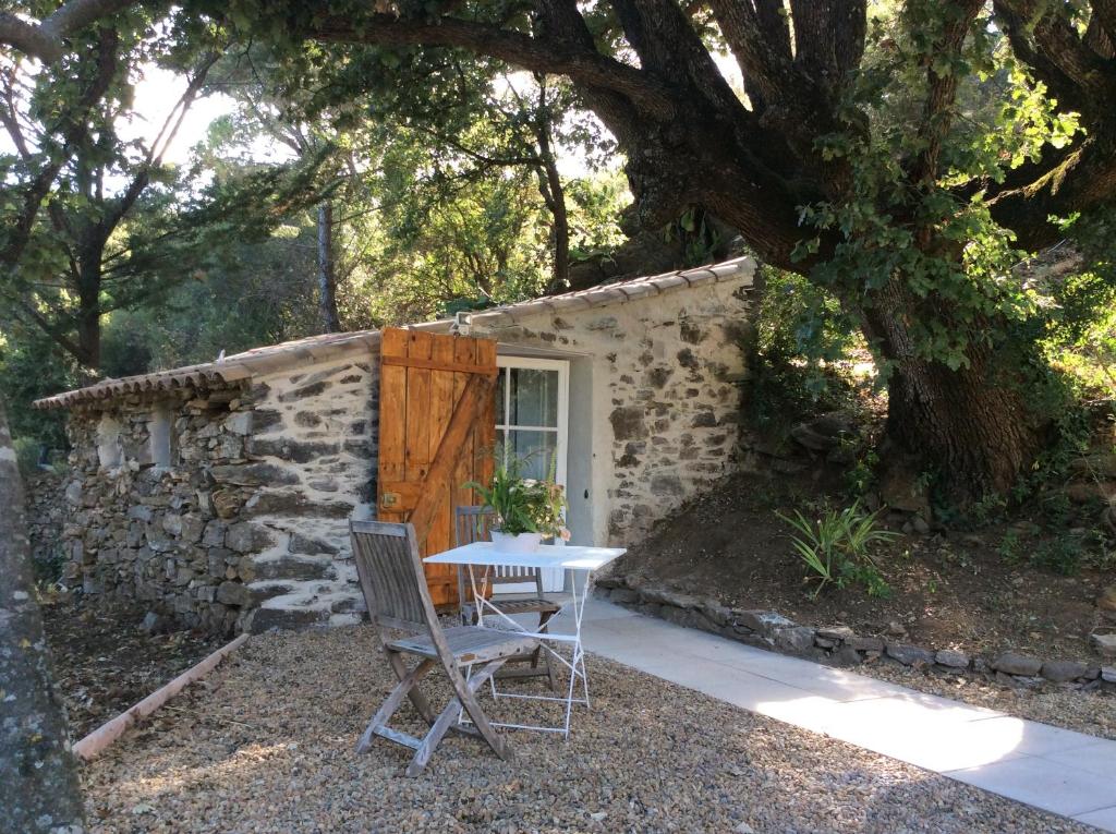 科洛布里埃La Petite Bergerie, Les Hautes Roches的石头建筑前的一张桌子和一把椅子