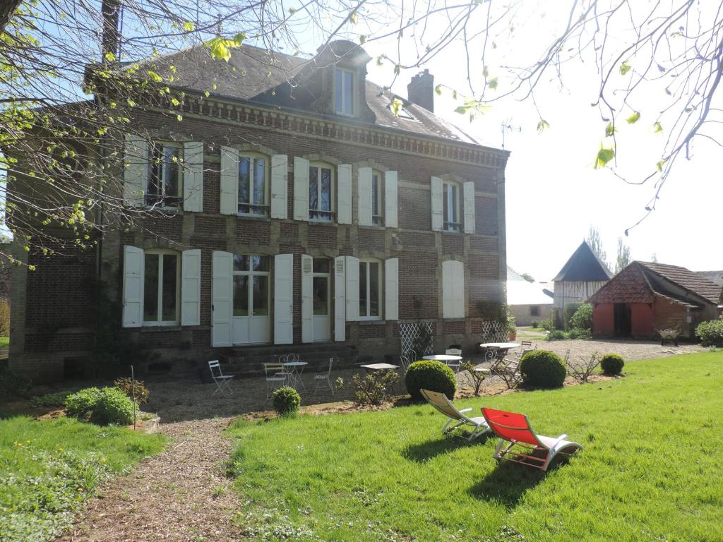 une chaise rouge en face d'une grande maison dans l'établissement Chambres d'Hôtes de la Bucaille, à La Bucaille