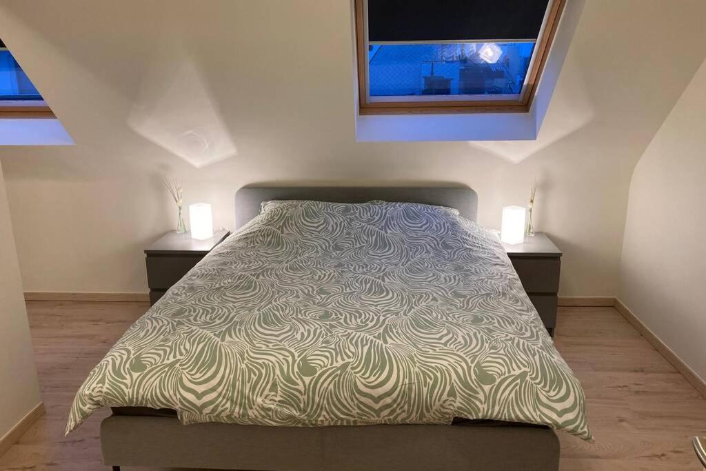 een bed in een slaapkamer met 2 nachtkastjes en 2 ramen bij Vakantieverblijf 'Mara Cinco' met ruim terras in Oostende in Oostende
