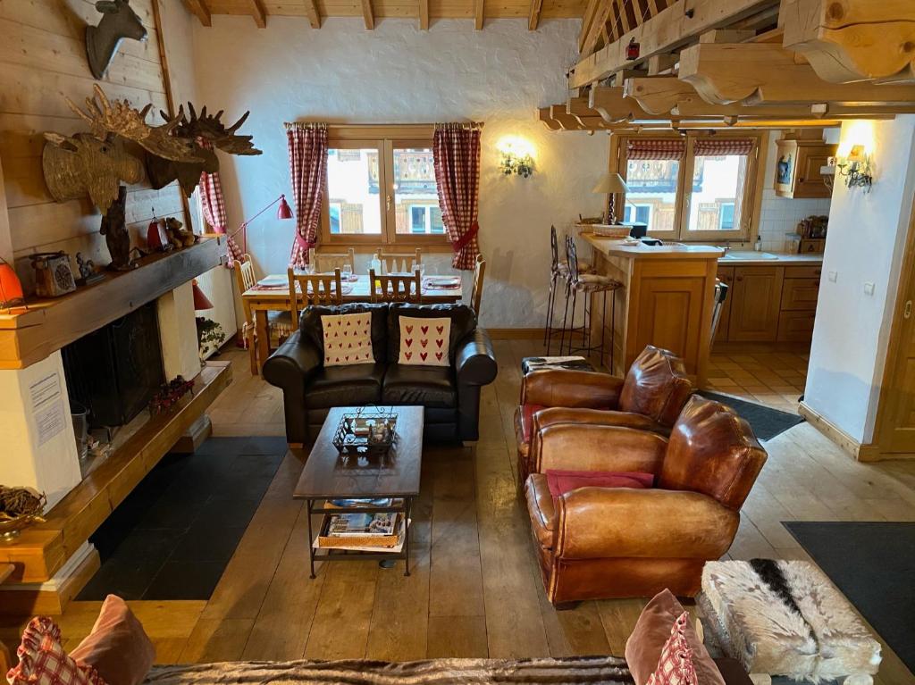 a living room with leather furniture and a kitchen at Chalet Roseau in Megève