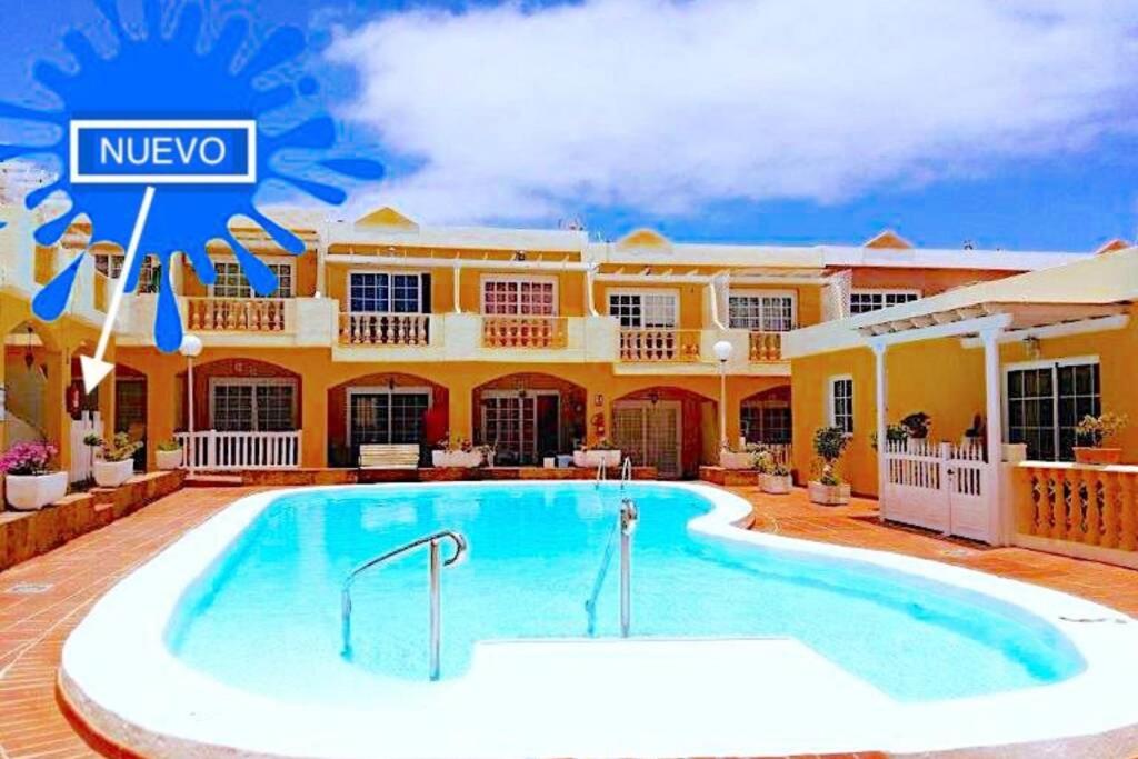 a swimming pool in front of a house at NEW Apartamento Caleta,Relax, Pool, Terrace, Wifi in Caleta De Fuste