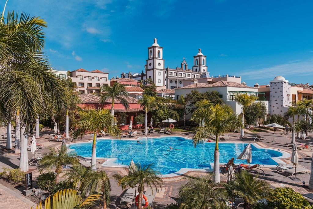 a view of a resort with a swimming pool and palm trees at Lopesan Villa del Conde Resort & Thalasso in Meloneras