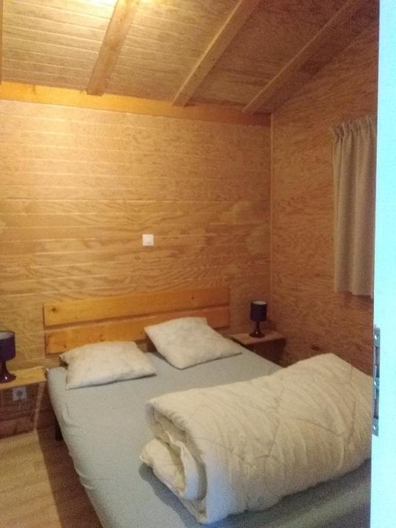 two twin beds in a room with wooden walls at chalet du camping la Porte St Martin in Saint-Martin-en-Vercors