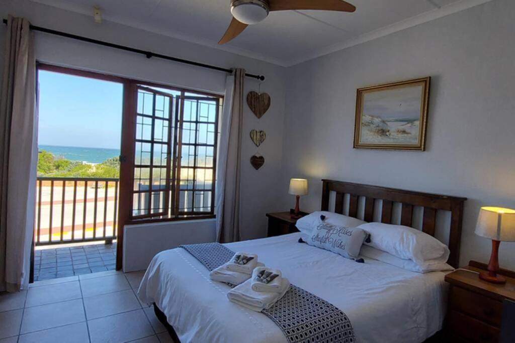 a bedroom with a bed and a large window at 12 Settler Sands Beachfront cottage with sea view in Port Alfred