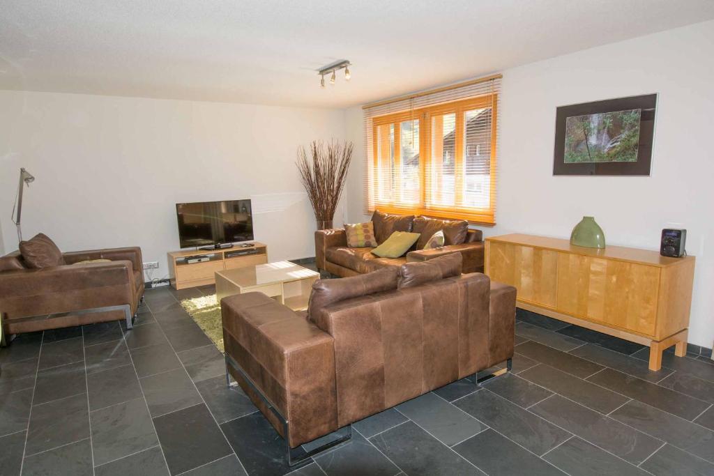 ein Wohnzimmer mit Sofas und einem Flachbild-TV in der Unterkunft Ferienwohnung Schützenrain in Adelboden