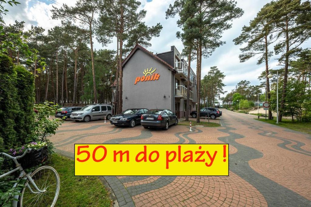 a building with cars parked in a parking lot at PONIK Apartamenty przy plaży in Pogorzelica