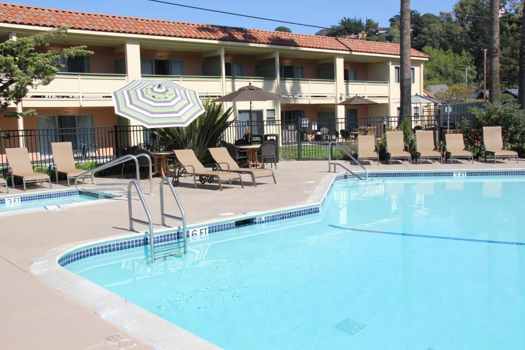 a pool in front of a hotel with chairs and an umbrella at Rio Sands Hotel in Aptos
