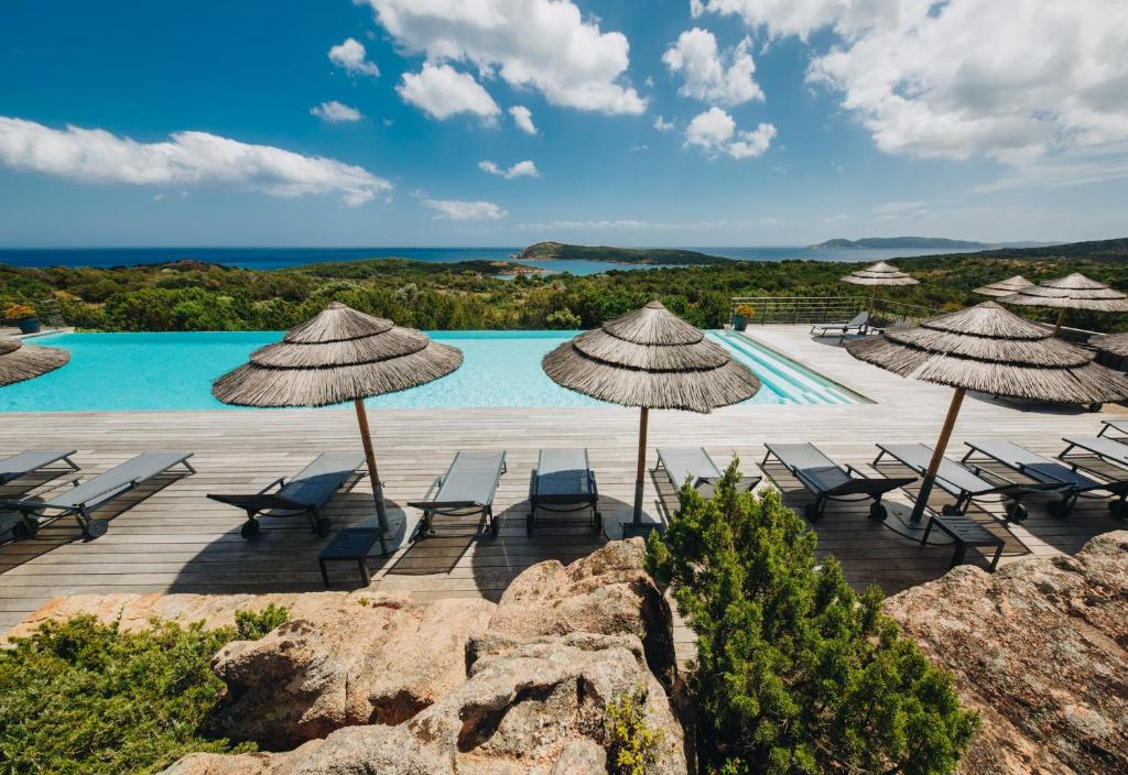 un complejo con piscina con sillas y sombrillas en Résidence Les Terrasses de Rondinara, en Bonifacio