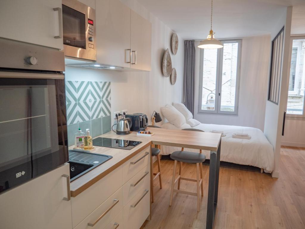 een kleine keuken met een tafel en een kamer met een bed bij Apparts Limogeanne - Clim - Centre historique in Périgueux