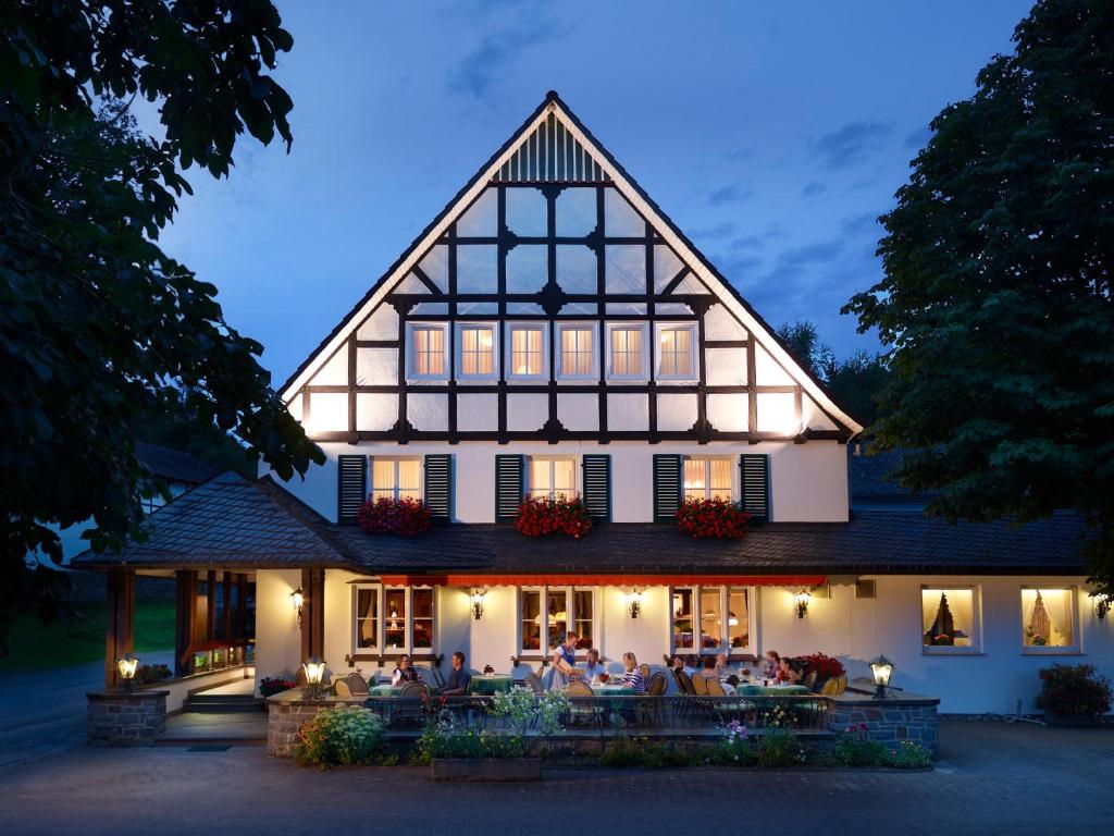 a large house with people sitting on the porch at Landhotel Halbfas-Alterauge in Drolshagen