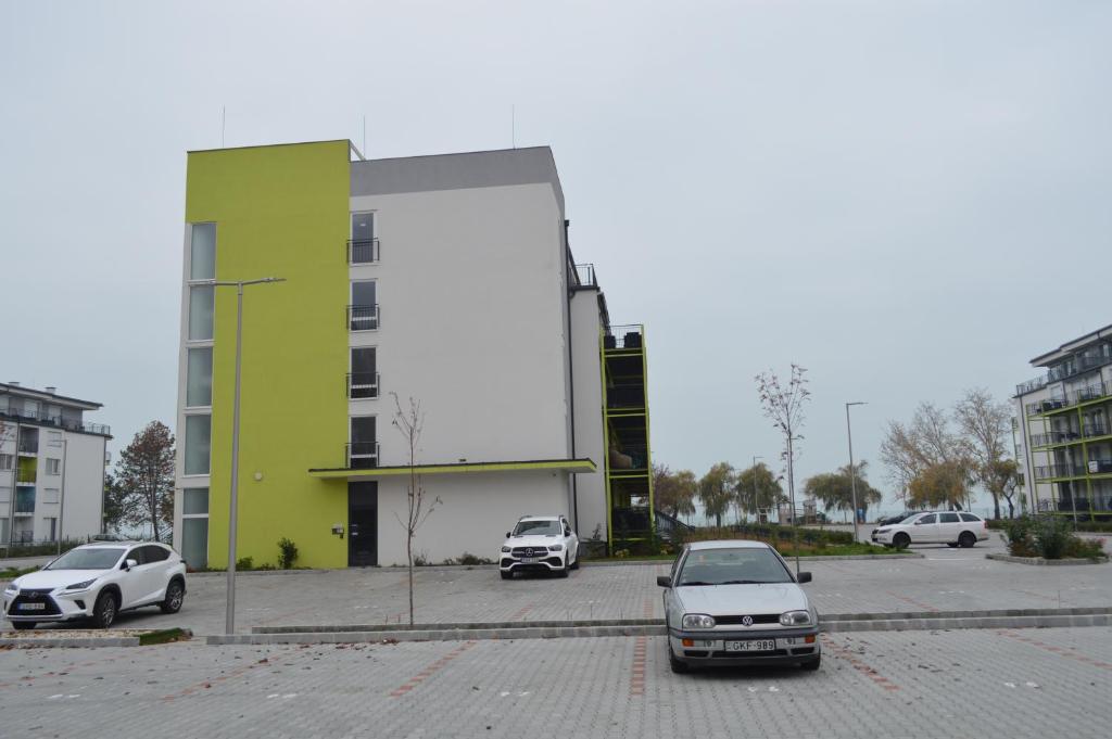 dos autos estacionados en un estacionamiento frente a un edificio en Siófok Ezüstpart Granada 3 Közvetlen Vizparti Földszinti Apartman en Siófok