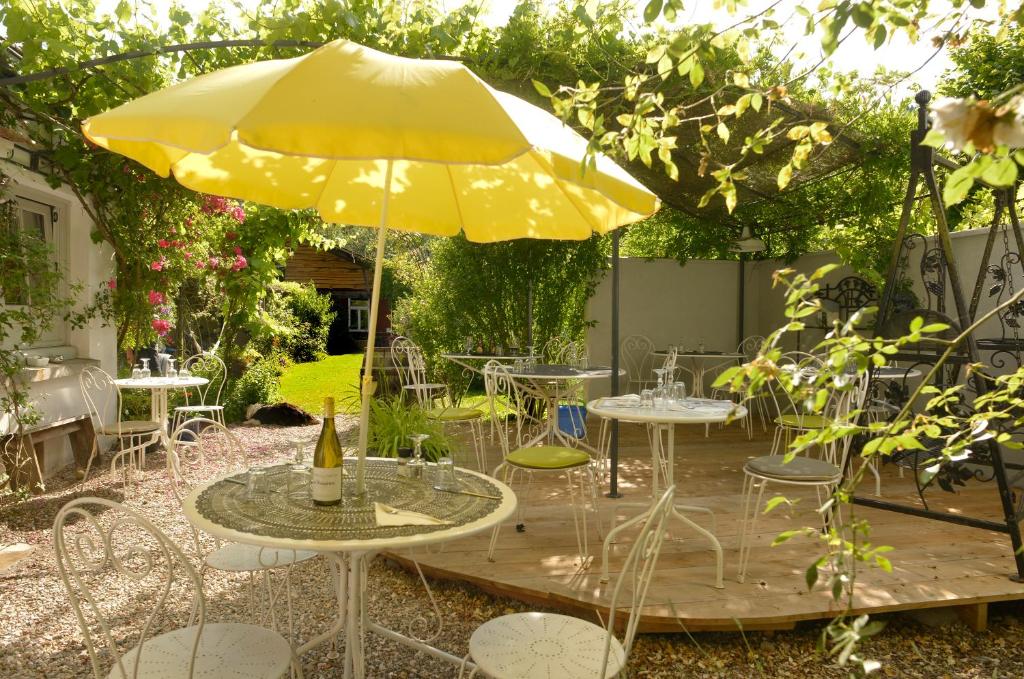 a patio with tables and a yellow umbrella at Chambre d`hôtes La Roseraie in Lucenay-lʼÉvêque