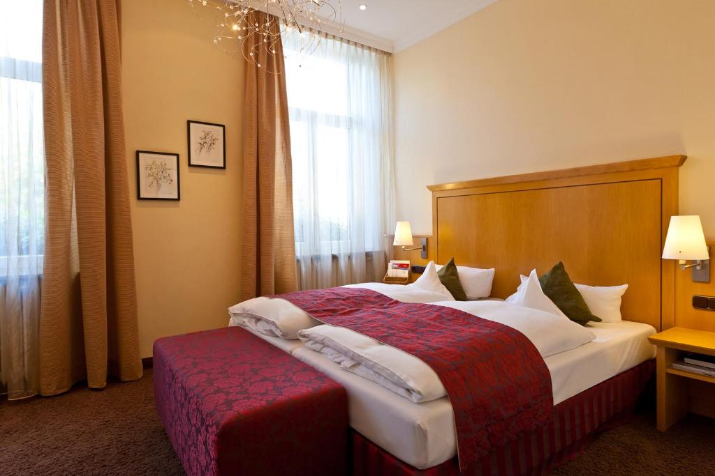 um quarto de hotel com uma cama grande e um banco vermelho em Just Sleep Trier em Trier