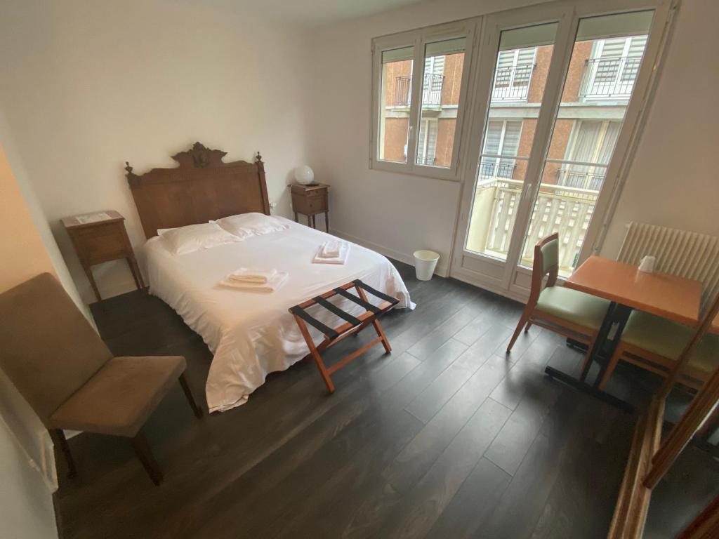 - une chambre avec un lit, une table et des chaises dans l'établissement Hôtel les Remparts, à Saint-Valery-en-Caux