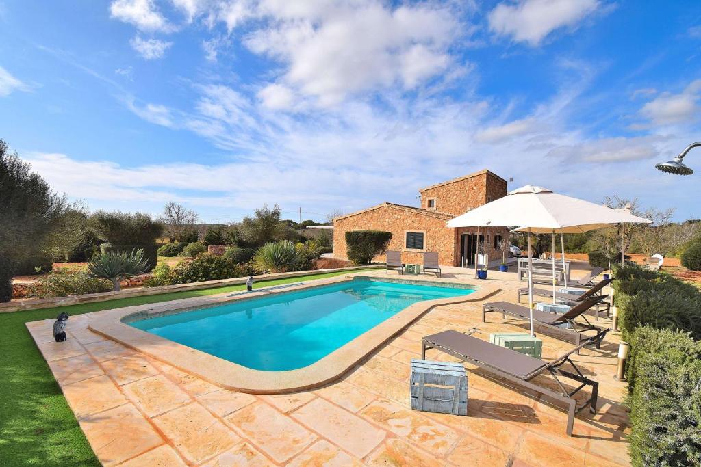 a swimming pool with an umbrella and a house at Finca Can Xesquet Camí de Morell 169 by Mallorca Charme in Ses Salines
