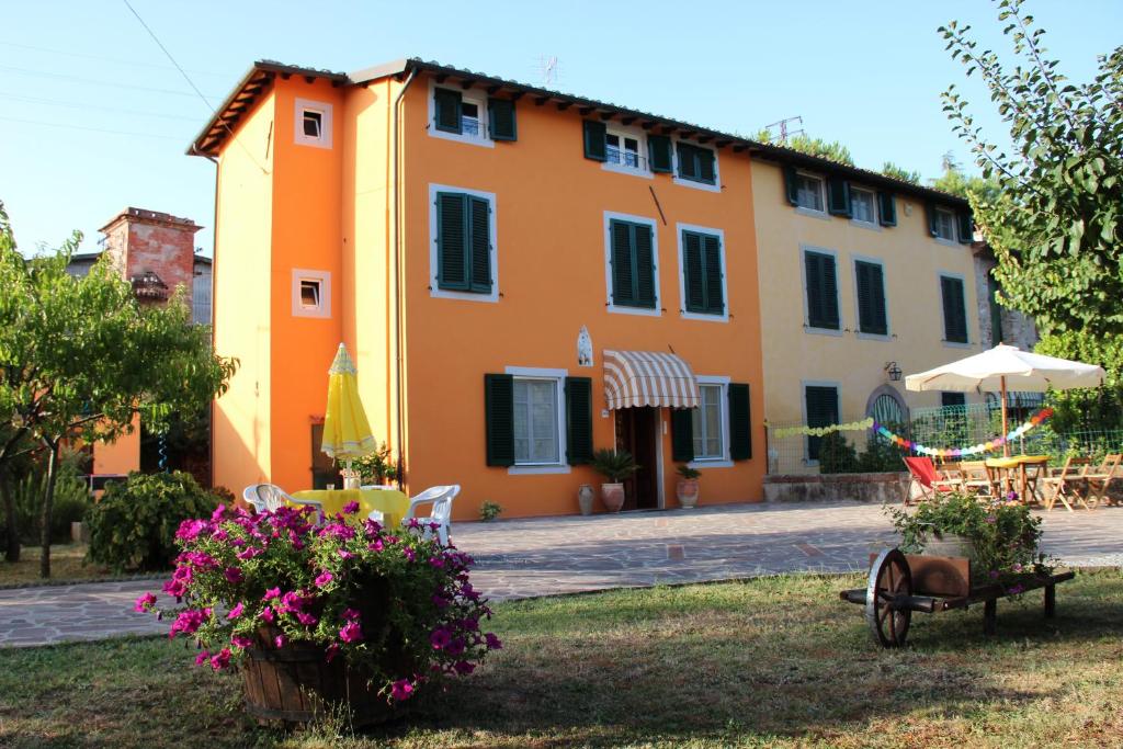 pomarańczowy dom ze stołem, krzesłami i kwiatami w obiekcie Bed & Breakfast Lucca Fora w mieście Capannori