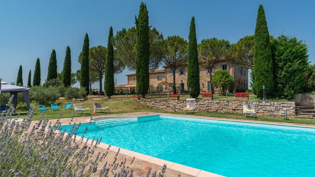 una piscina frente a una casa con árboles en CASALE BROLIO 12&2, Emma Villas, en Cortona