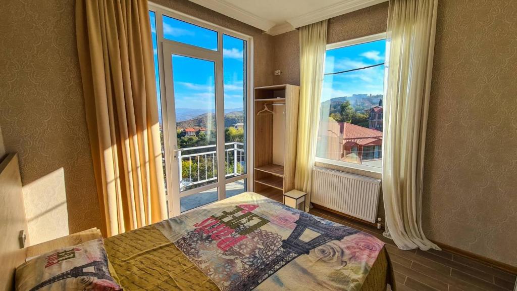 a bedroom with a bed and a large window at Guest House Alazani Valley in Sighnaghi