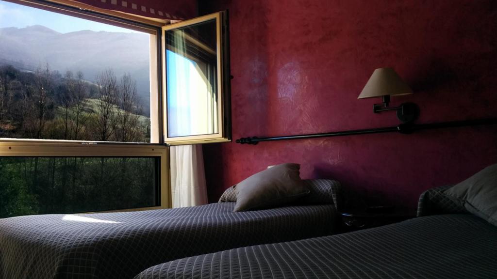 a bedroom with a bed and a window at Hotel Lena in Pola de Lena