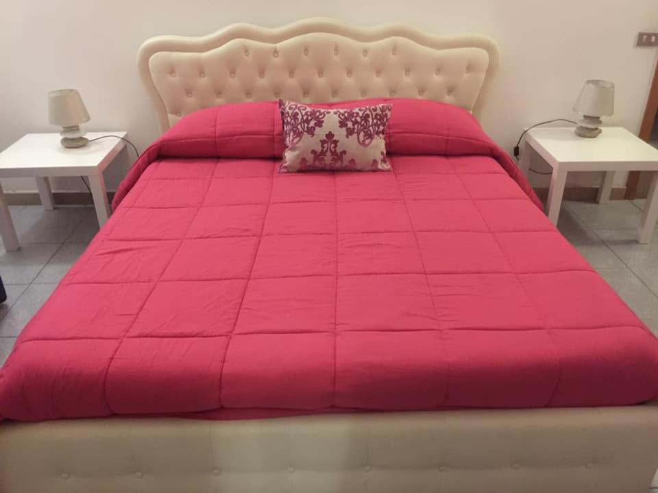 een roze bed met twee nachtkastjes en twee tafels bij B&B Il Tulipano in Taranto