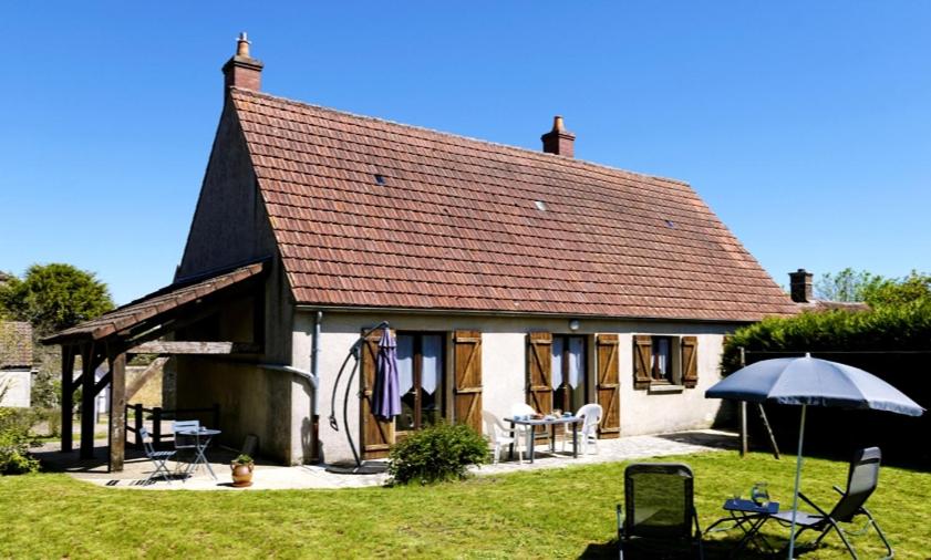 ein kleines Haus mit einem Regenschirm und einigen Stühlen in der Unterkunft La Garçonnière in Treigny