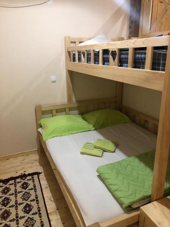 a bunk bed with two green pillows on it at Salaš Gnijezdo in Bačka Palanka