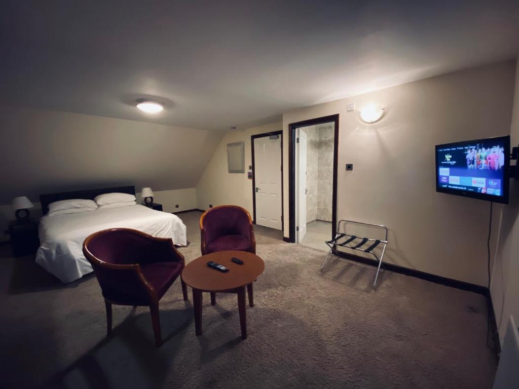a hotel room with a bed and a tv and chairs at Clifton House Brighton in Portslade