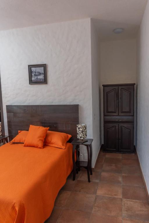 una camera con un letto arancione e un tavolo di Hostal Maria Tepozteca a Tepoztlán
