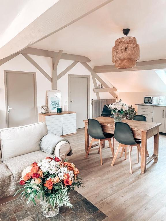 a living room with a couch and a table with flowers at Chambres Privées dans une maison de charme in Saint-Brice-sous-Forêt