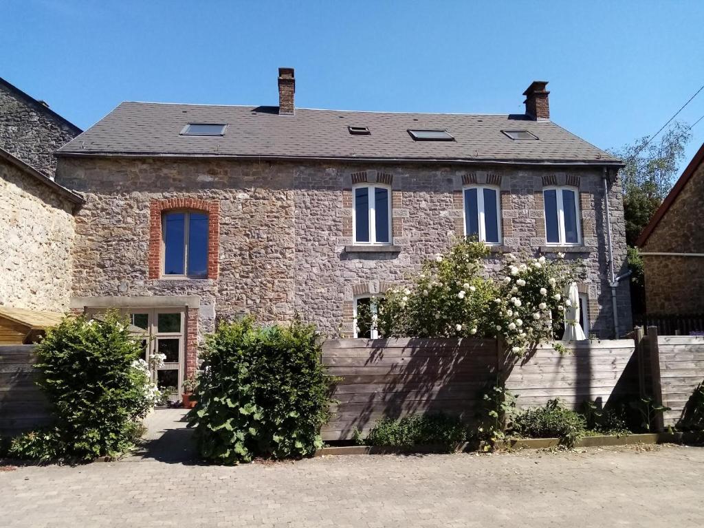 una vecchia casa in pietra con cespugli di fronte di Le petit gîte de Maurenne a Hastière-Lavaux