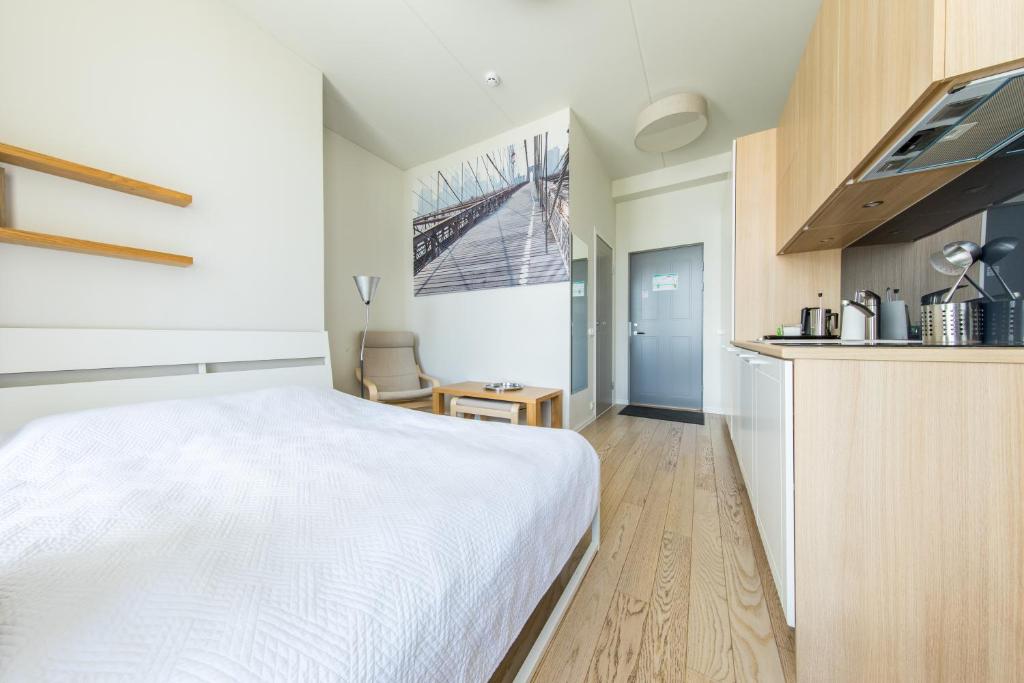 Cet appartement comprend une chambre avec un lit blanc et une cuisine. dans l'établissement Mere Street Stylish Studio near Rotermanni quarter, à Tallinn