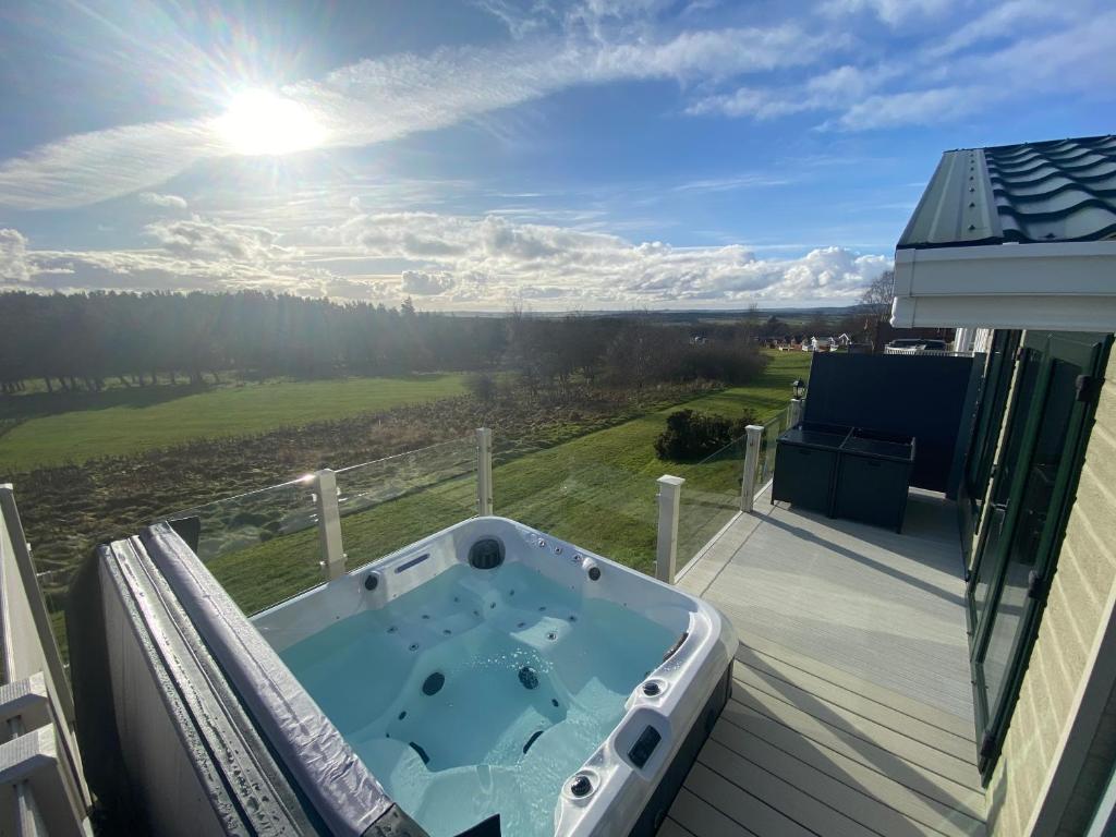 bañera de hidromasaje en el balcón de una casa en Hot Tub Lodge with Panoramic Views & Free Golf, en Swarland