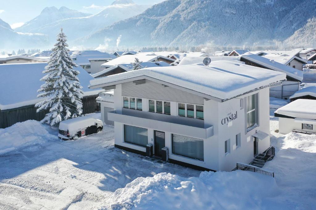 une maison blanche dans la neige avec des montagnes en arrière-plan dans l'établissement Apart Crystal, à Längenfeld
