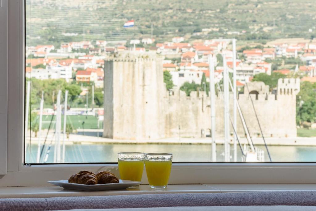 einen Tisch mit zwei Gläsern Orangensaft und einem Teller Gebäck in der Unterkunft Kamerlengo in Trogir