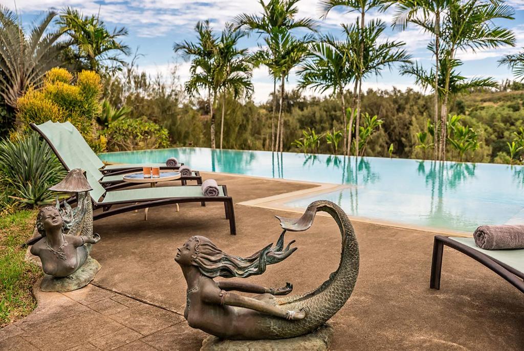 um pátio com uma estátua de uma mulher ao lado de uma piscina em Hawaii Island Retreat at Ahu Pohaku Ho`omaluhia em Kapaau