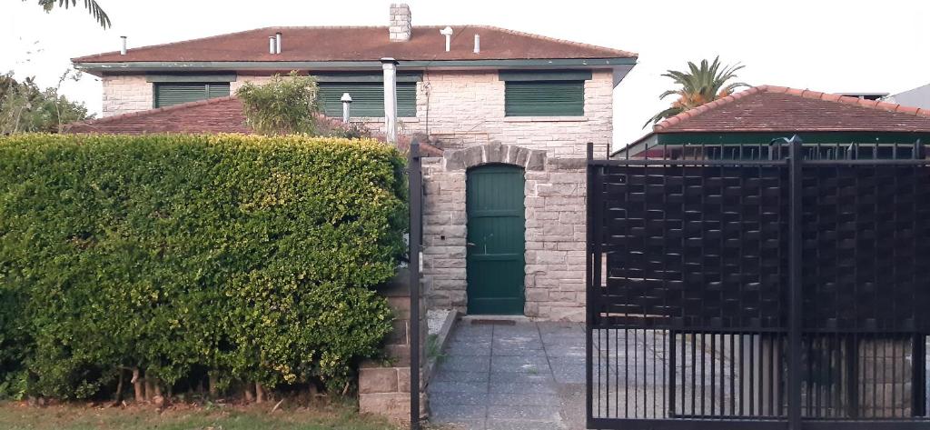 una casa de ladrillo con una puerta verde y un seto en Casa barrio Los Troncos "La Magnolia" en Mar del Plata