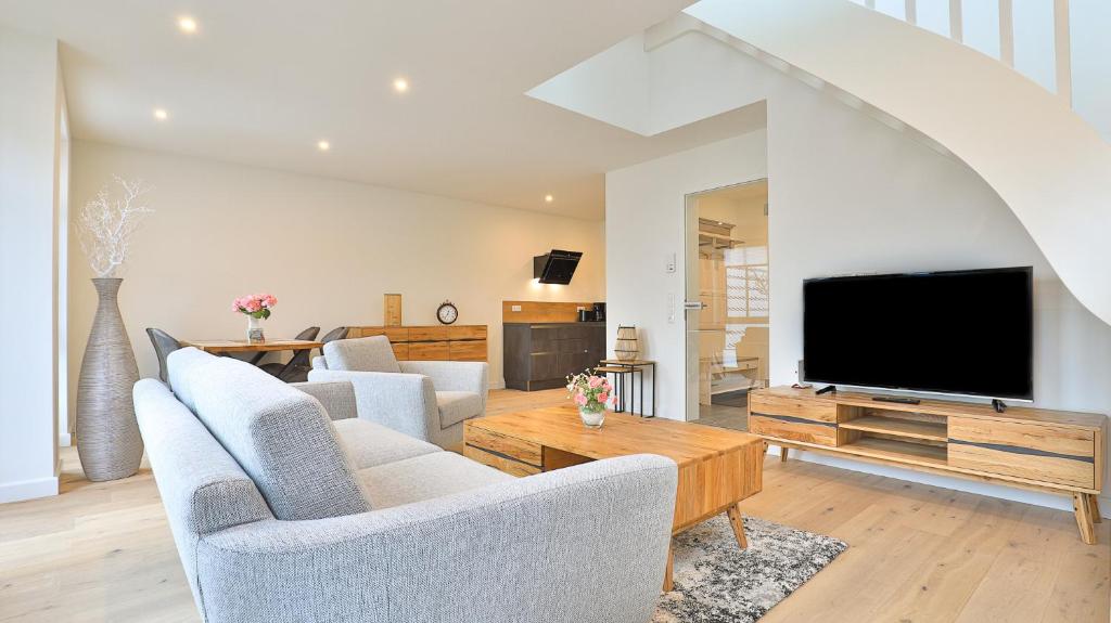ein Wohnzimmer mit Sofas und einem Flachbild-TV in der Unterkunft Strandhaus Zingst Penthouse Seeblick in Zingst