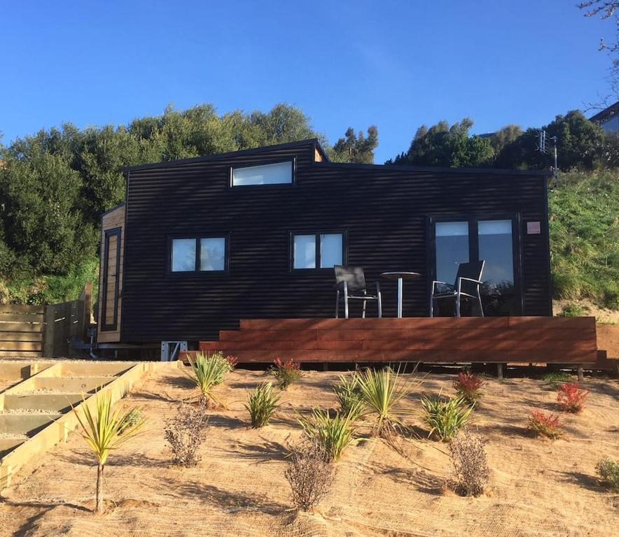 a small black house in the middle of a field at Big View from a Tiny House, Cashmere in Christchurch