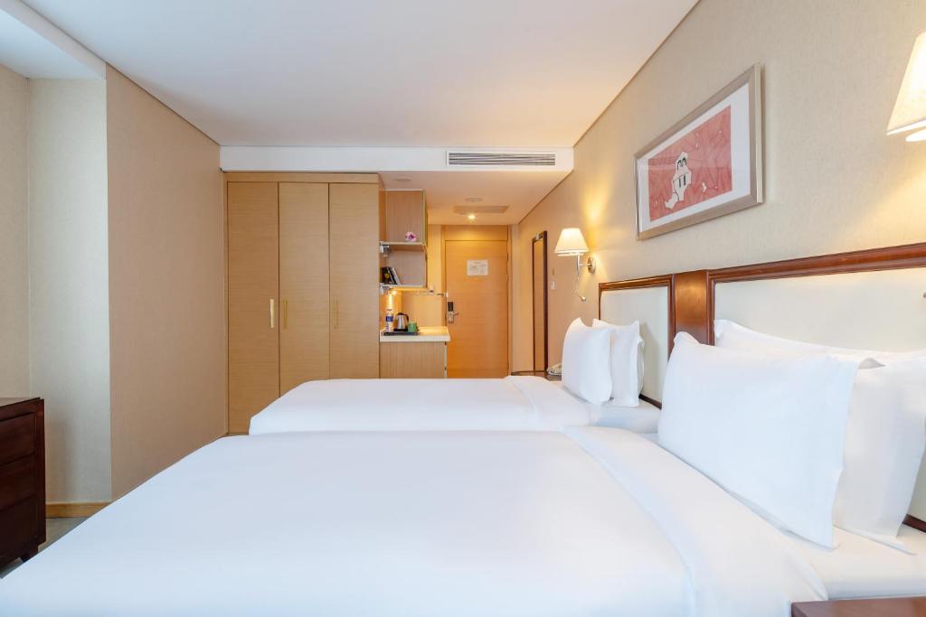 a hotel room with two beds with white pillows at Regal Plaza Hotel & Residence in Shanghai