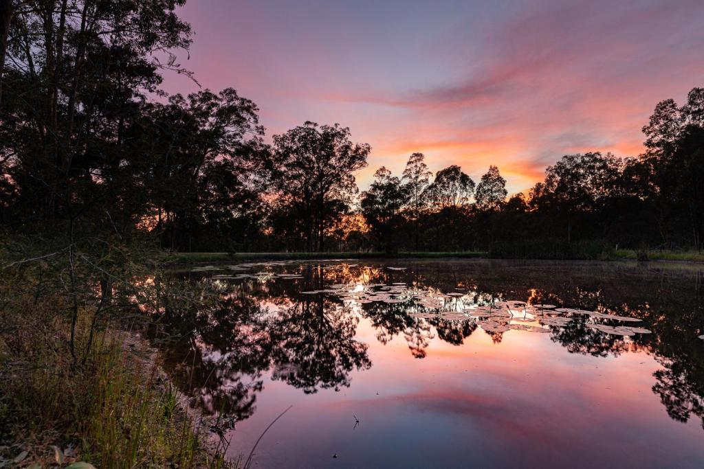 a sunset over a lake with trees and clouds at Hunter Hideaway Cottages in Rothbury