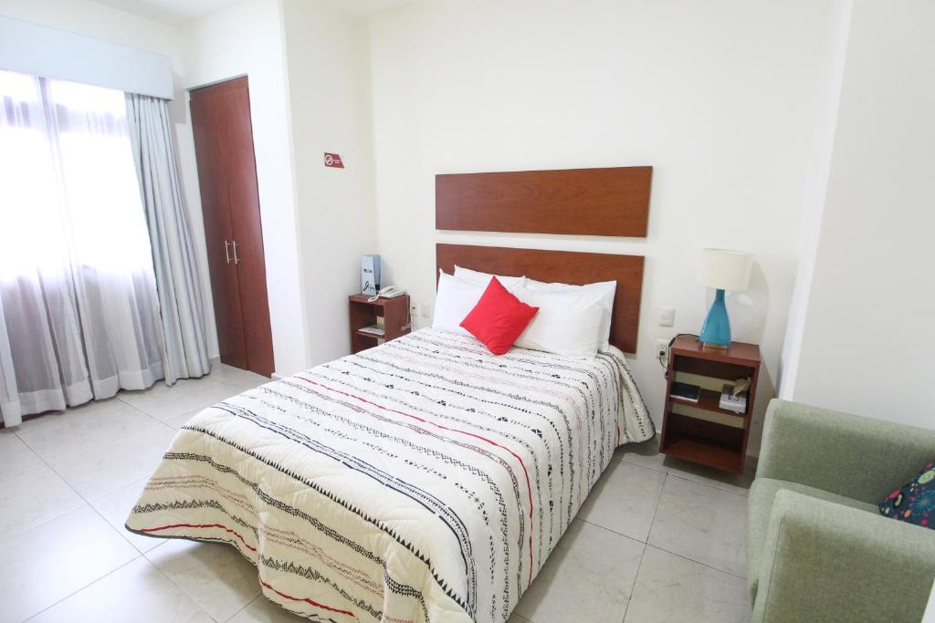 ein Schlafzimmer mit einem Bett mit zwei roten Kissen in der Unterkunft Casa de la iaia Hotel in Orizaba