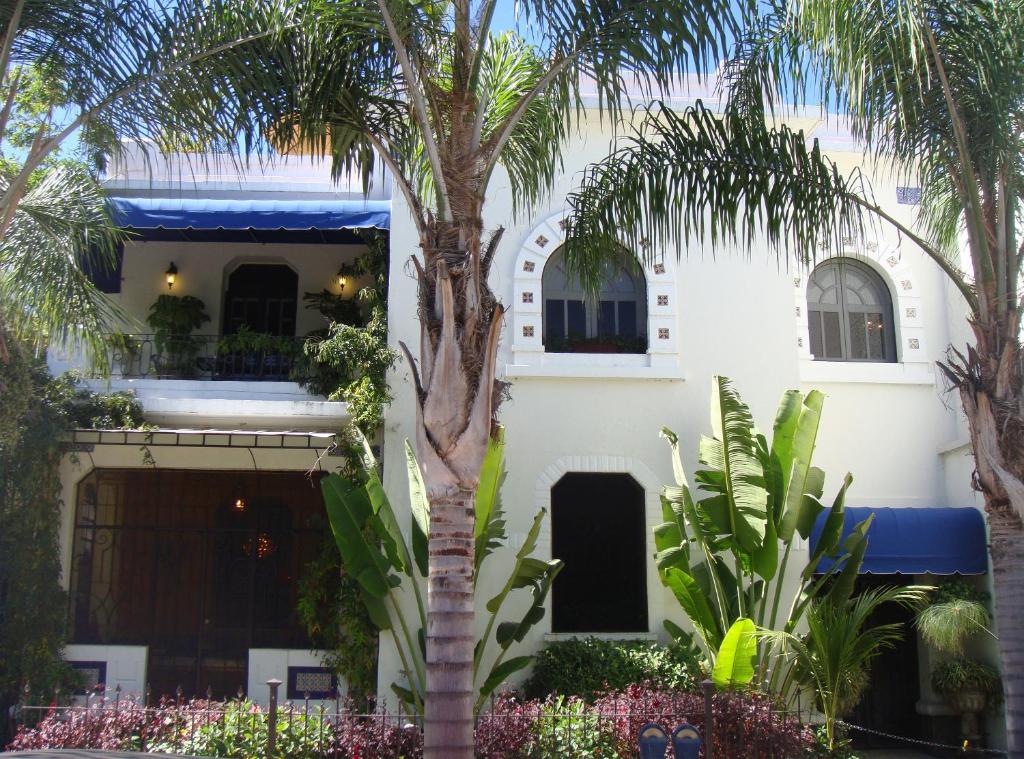 a white building with palm trees in front of it at La Perla Hotel Boutique B&B in Guadalajara