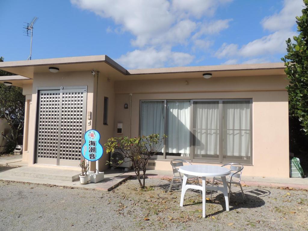 a house with a table and chairs in front of it at びせ崎の宿　海潮音 in Motobu