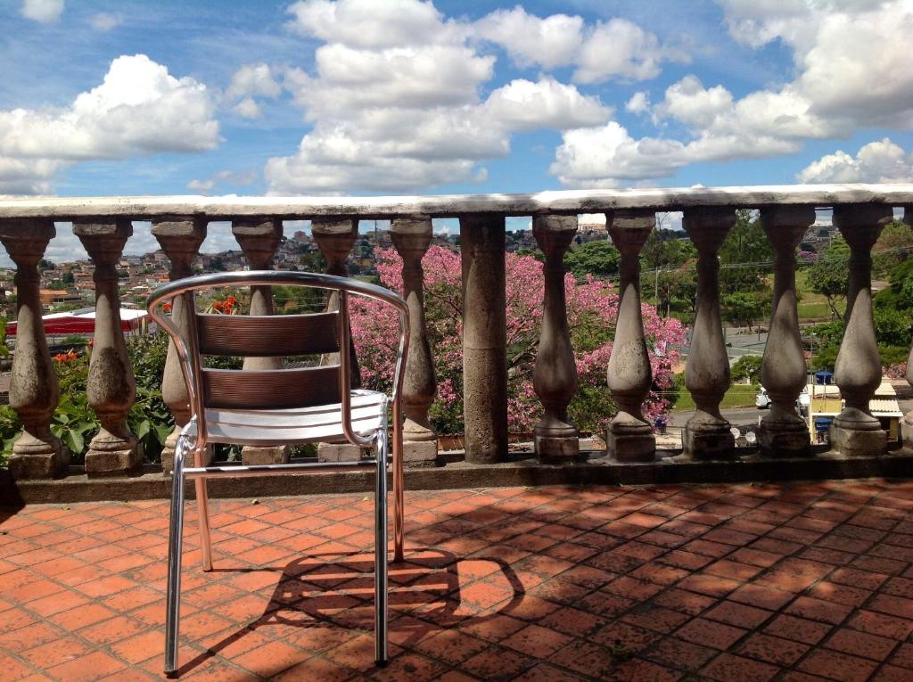een stoel op een balkon met roze bloemen bij Pousada Del Rey in Belo Horizonte